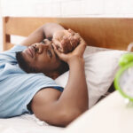 Black man in bed suffering from sleep disorder